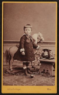 Hofmannsthal als Kleinkind, stehend, mit Spielzeugpferd im Atelier