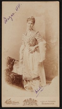 Elisabeth (Lisl) Nicolics im orientalisch besticktem Kleid, vor Teppichen, mit Widmung