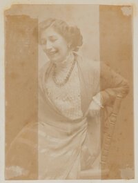 Gerty von Hofmannsthal lächelnd auf einem Holzstuhl sitzend